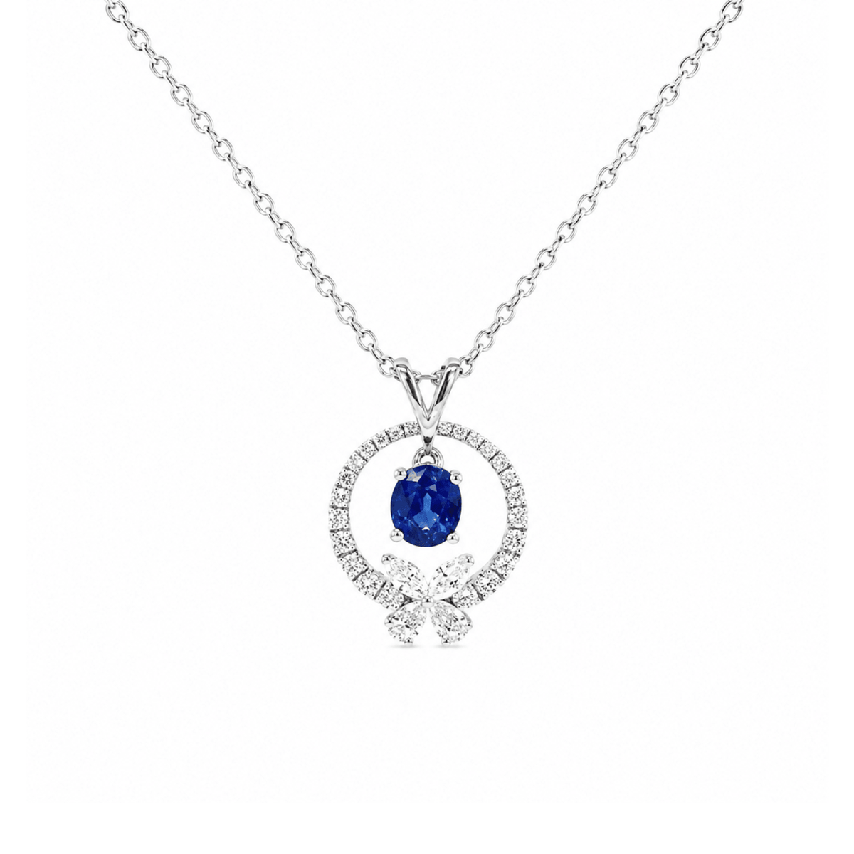 18K white gold pendant necklace featuring a center oval-cut sapphire within an open diamond-set circle, accented with a small diamond flower cluster at the base, suspended from a diamond-station chain.